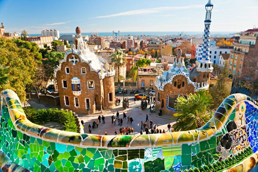 a group of people in a pool of water with Park Güell in the background
